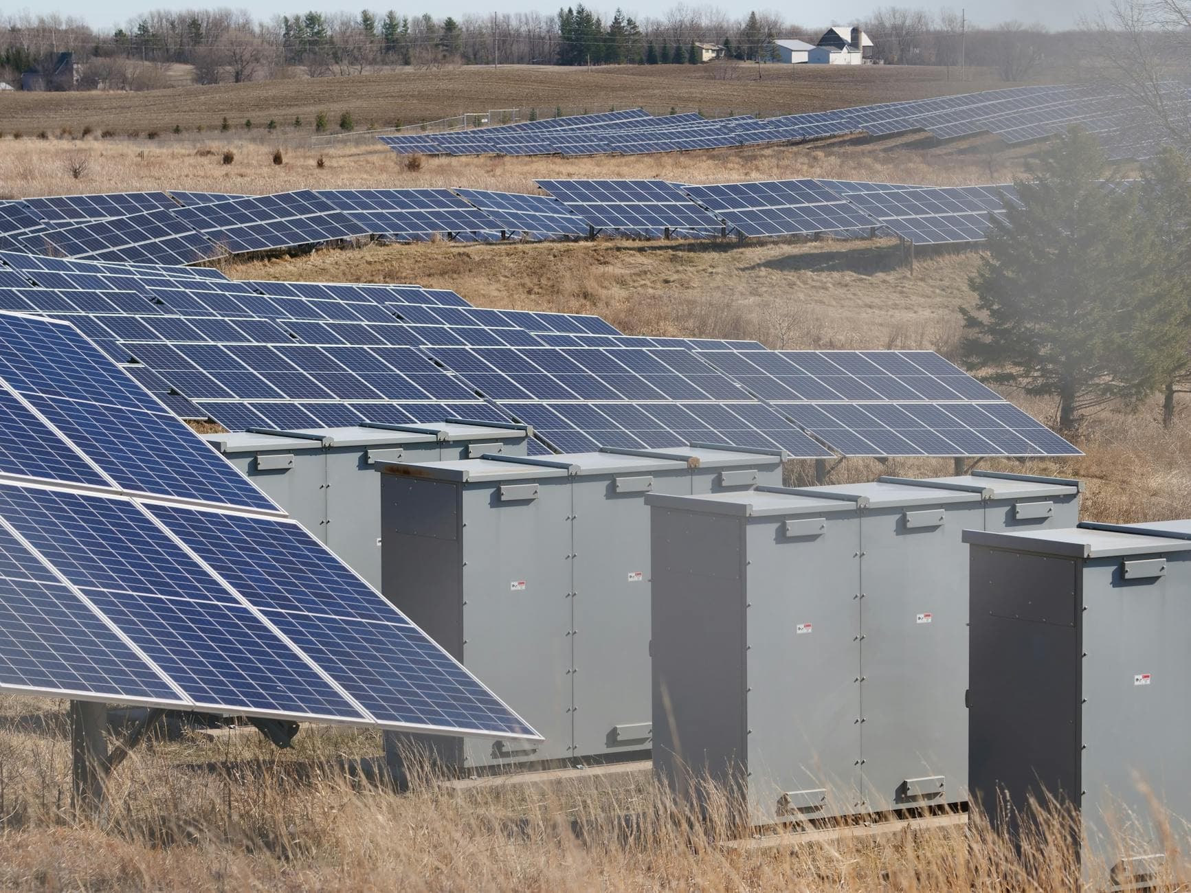 Utility-scale solar farm with rows of photovoltaic panels and inverter cabinets.