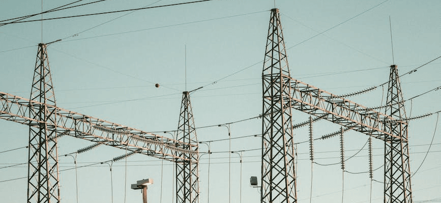Overhead electrical transmission lines and lattice towers running through open terrain.